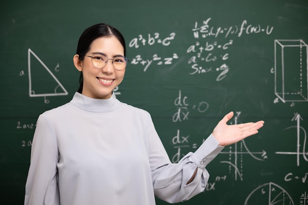 Giovane insegnante asiatica che apre il palmo della mano e videoconferenza con la fotocamera dello studente Insegnante femminile che forma la matematica nella lavagna in classe dal corso online