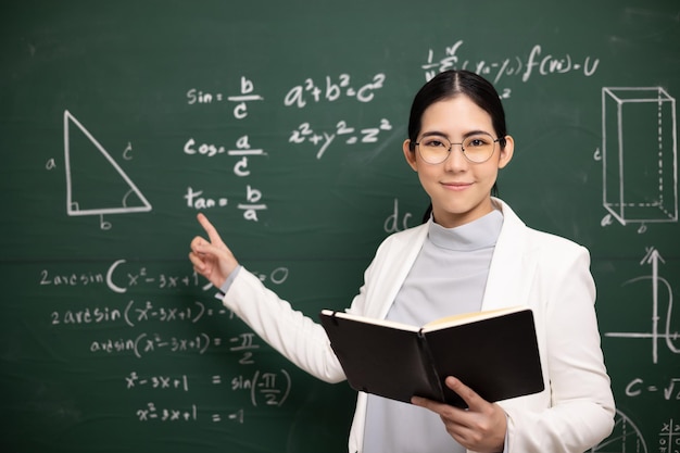 Giovane insegnante asiatica che insegna a tenere libro e videoconferenza con la fotocamera degli studenti Insegnante femminile che forma la matematica in classe lavagna dal corso online