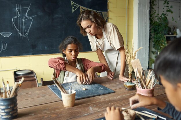 Giovane insegnante di artigianato che aiuta uno degli alunni a lezione