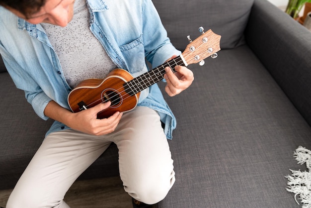 Giovane irriconoscibile seduto su un divano che suona l'ukulele