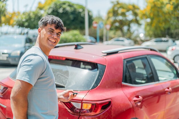 Giovane ispanico all'aperto con le chiavi dell'auto con un'espressione felice