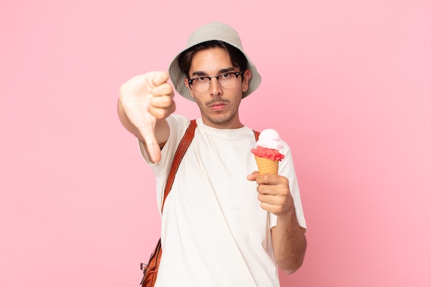 Giovane ispanico che si sente arrabbiato, mostra i pollici in giù e tiene in mano un gelato