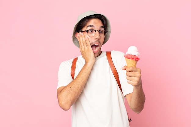 Giovane ispanico che si sente felice, eccitato e sorpreso e tiene in mano un gelato