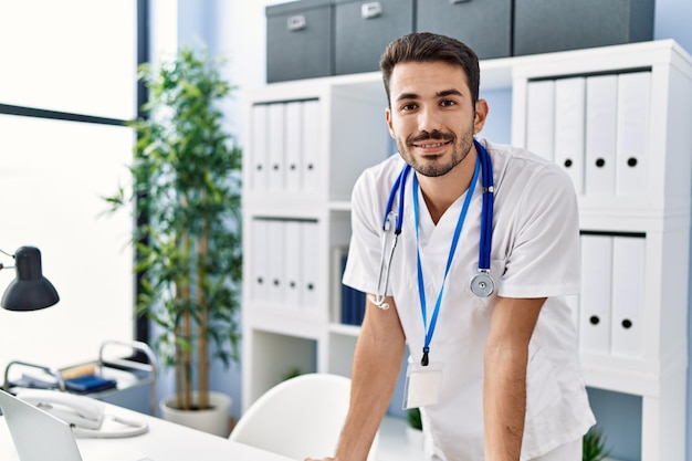 Giovane ispanico in uniforme da dottore in piedi in clinica