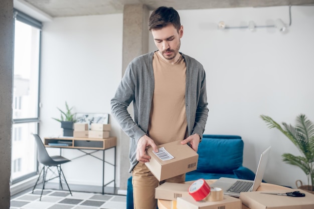 Giovane lavoratore del negozio online che prepara le merci per il trasporto