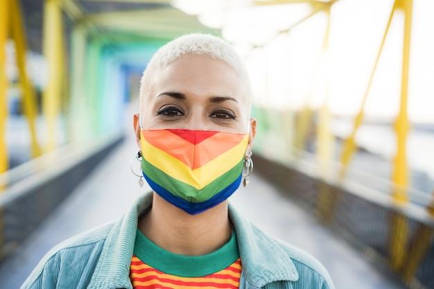 Giovane lesbica che indossa la maschera dell'orgoglio della bandiera arcobaleno LGBT - Focus on face