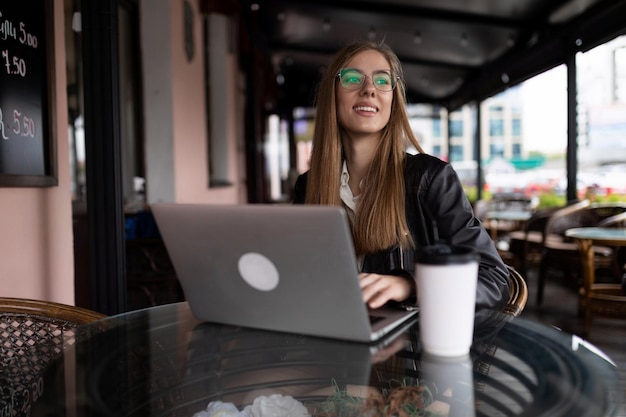 Giovane libero professionista femminile che lavora a distanza su un computer portatile in un caffè