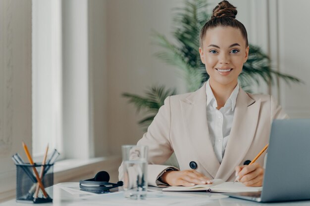 Giovane libero professionista femminile di successo che annota le informazioni nel blocco note