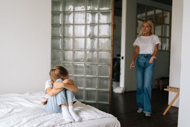 Giovane madre aggressiva pazza che entra nella stanza dei bambini rimproverando alzando la voce gridando e gesticolando con le mani alla figlia testarda e difficile