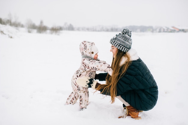 giovane madre alla moda che gioca con la piccola figlia all'aperto in inverno.