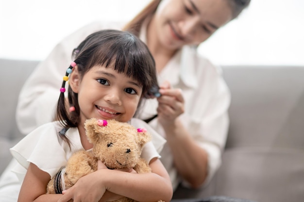 Giovane madre asiatica che lega i capelli della figlia