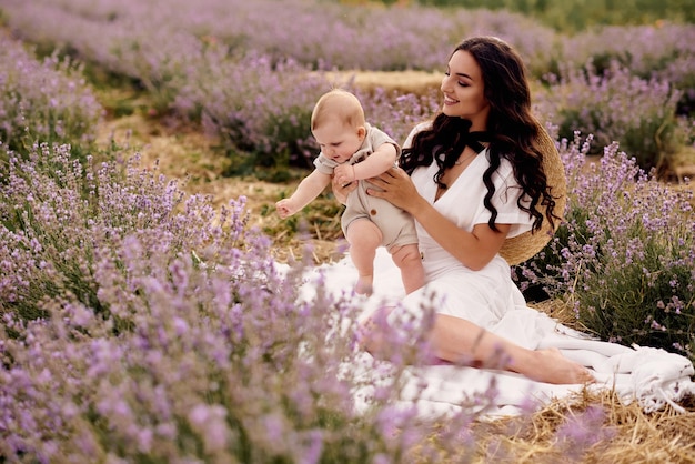 Giovane madre attraente che gioca con il suo bambino in un campo di lavanda