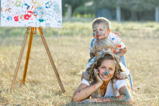 Giovane madre attraente divertirsi con i suoi figli al parco. Divertimento allegro della famiglia all'aperto. La mamma gioca con i suoi figli.