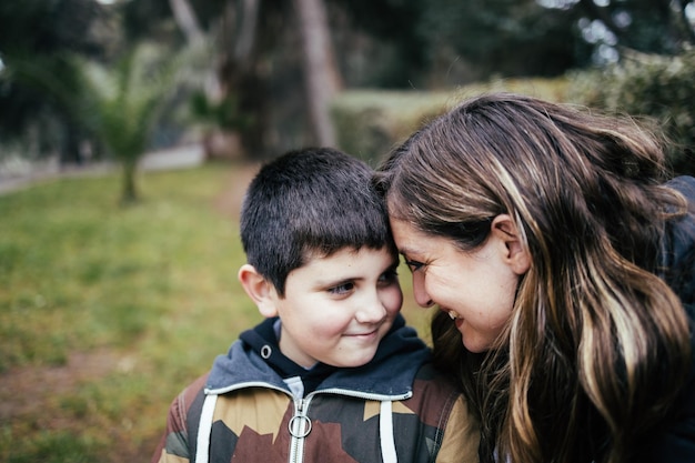 Giovane madre bionda latina che abbraccia e ride con il suo giovane figlio nel parco. Famiglia a genitore unico