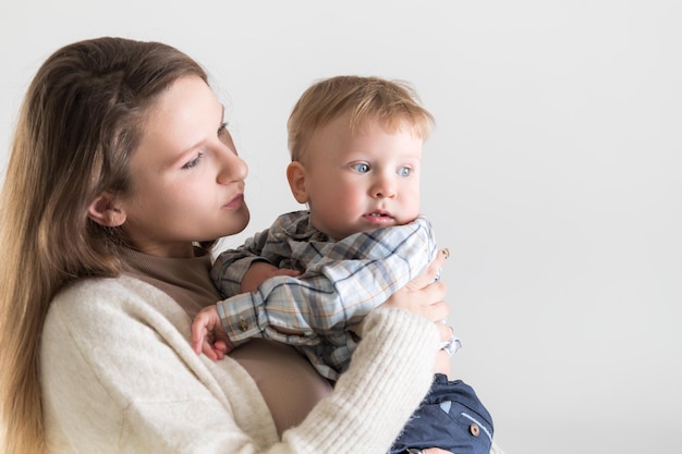 Giovane madre caucasica che tiene un bambino in braccio su uno sfondo bianco