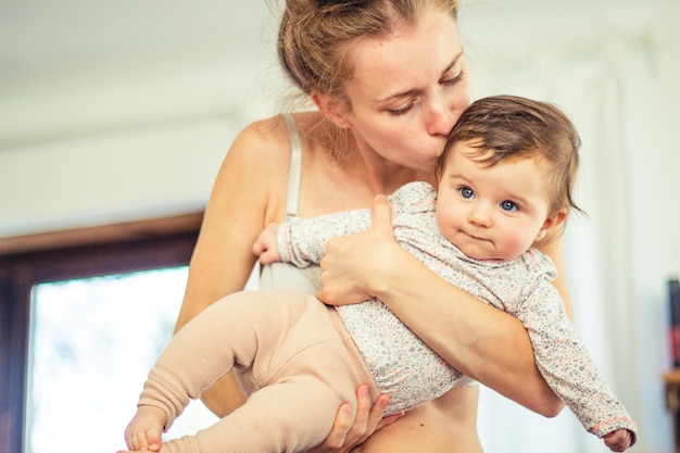 Giovane madre che bacia e tiene in braccio il suo bambino