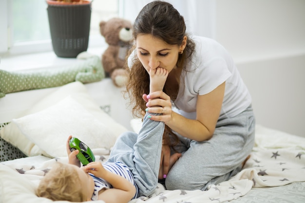 Giovane madre che bacia il suo bambino sdraiato sul letto