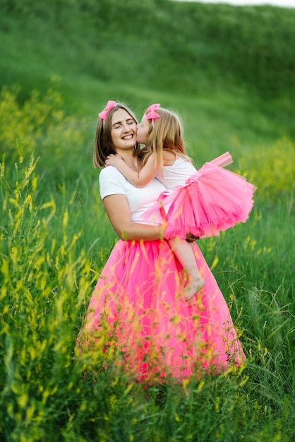 Giovane madre che bacia una ragazza nel parco Giovane bella mamma con sua figlia con gli stessi vestiti Famiglia stesso look Stile di moda Abbigliamento per genitore e figlio