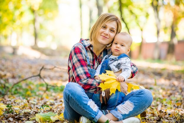 giovane madre che gioca con il bambino nel parco in autunno