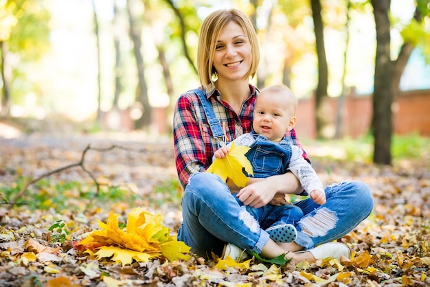 giovane madre che gioca con il bambino nel parco in autunno