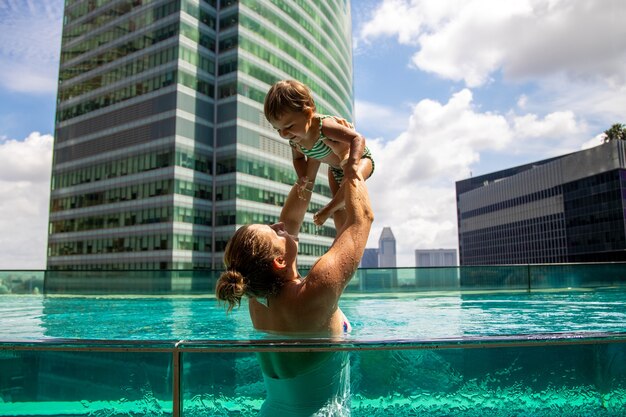 giovane madre che gioca in piscina con la piccola figlia ...