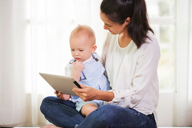 Giovane madre che mostra il computer tablet con un video animato sullo schermo al suo bambino