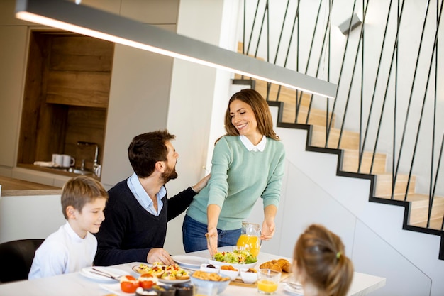 Giovane madre che prepara la colazione per la sua famiglia nella cucina moderna