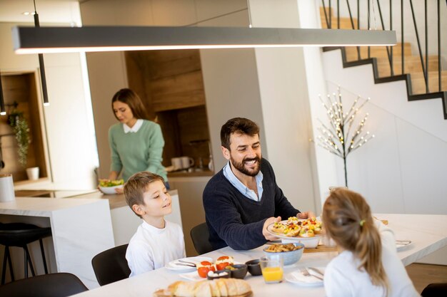 Giovane madre che prepara la colazione per la sua famiglia nella cucina moderna