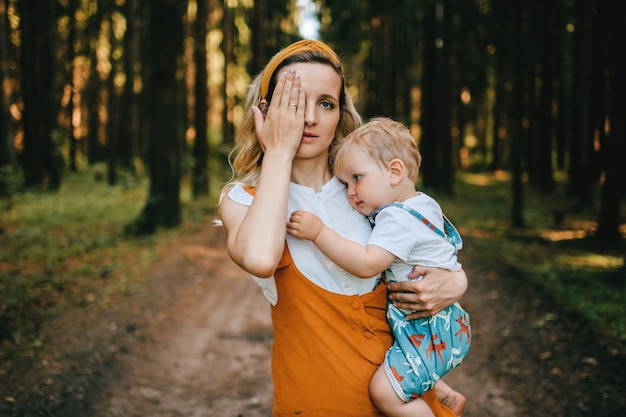 Giovane madre che tiene il suo adorabile figlio a nella foresta