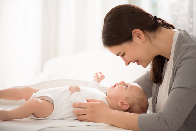 Giovane madre che tiene il suo bambino in camera da letto.