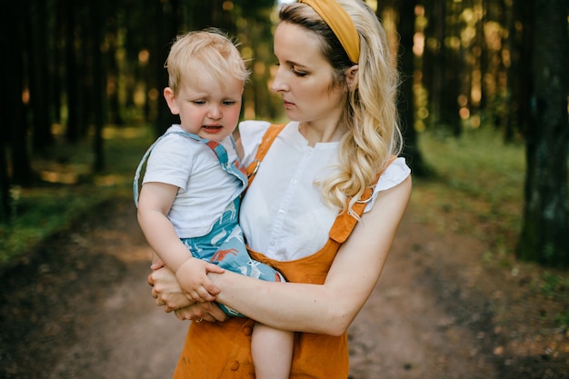 Giovane madre che tiene il suo figlio che piange nella foresta