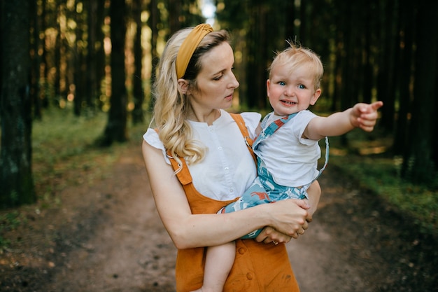 Giovane madre che tiene il suo figlio divertente nella foresta