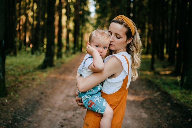 Giovane madre che tiene il suo figlio divertente nella foresta