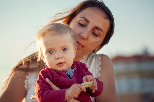 Giovane madre con il suo bambino carino, godendo la giornata di sole sopra campo estivo.