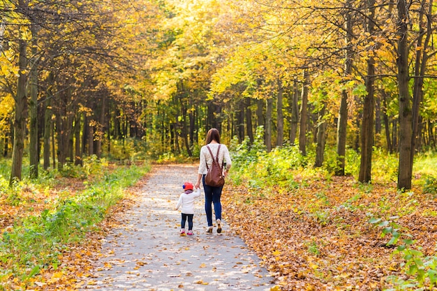 Giovane madre con la sua piccola bambina nel parco autunnale.