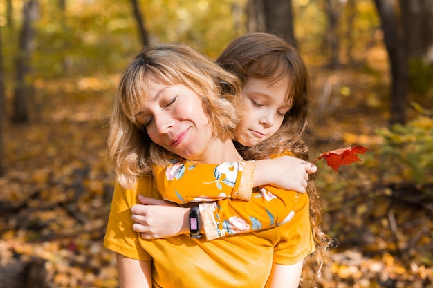 Giovane madre con la sua piccola figlia in un parco autunnale. Concetto di stagione autunnale, genitorialità e bambini.