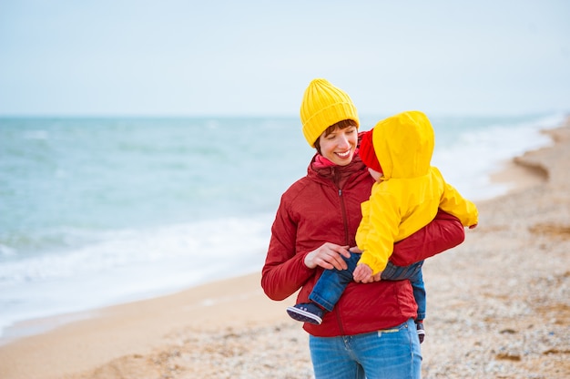 Giovane madre con suo figlio in riva al mare in inverno