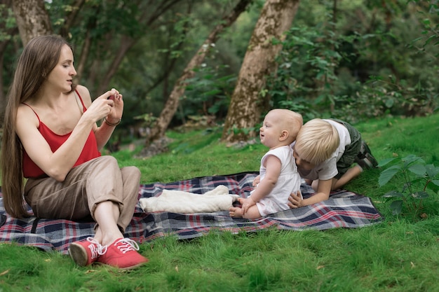 Giovane madre di scattare foto dei suoi figli sul telefono. Picnic con tutta la famiglia.