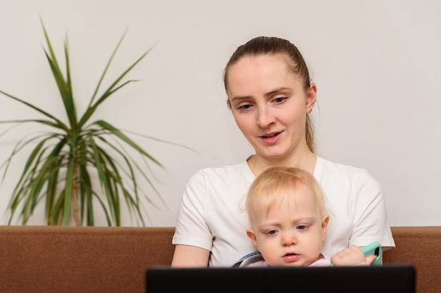 Giovane madre e bambino che si siedono vicino al computer portatile. Giochi educativi per computer per bambini