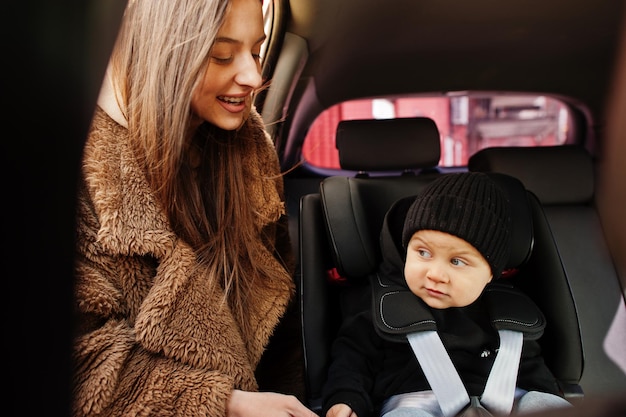 Giovane madre e bambino in auto Seggiolino per bambini sulla sedia Concetto di guida sicura