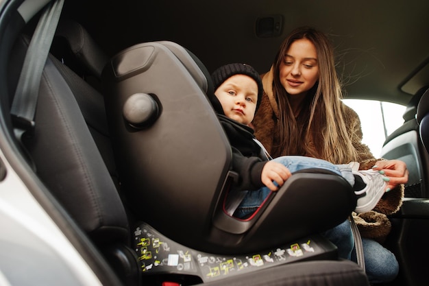 Giovane madre e bambino in auto Seggiolino per bambini sulla sedia Concetto di guida sicura