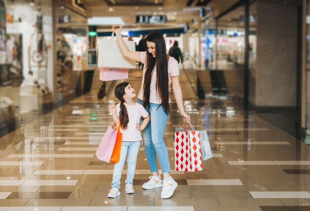 Giovane madre e figlia che tengono i sacchetti della spesa che comperano nel centro commerciale Acquisto della famiglia