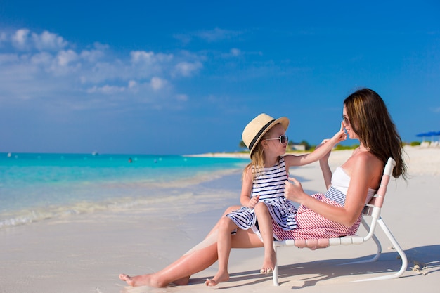 Giovane madre e piccola figlia adorabile alla spiaggia tropicale