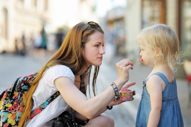 Giovane madre e sua figlia che mangiano il gelato all&#39;aperto