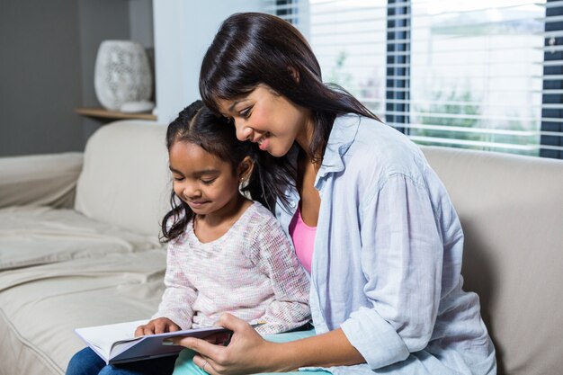 Giovane madre felice che legge un libro con sua figlia