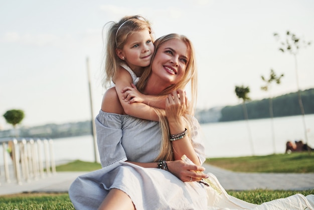 Giovane madre felice con una figlia allegra in un parco vicino all'acqua