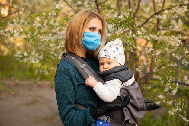 Giovane madre in maschera medica con figlio piccolo che gioca nel parco