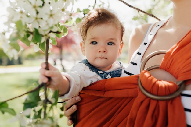 Giovane madre irriconoscibile con il suo bambino neonato in fionda