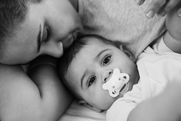 Giovane madre sdraiata a letto con il figlio a letto a casa Focus sugli occhi del bambino Modifica in bianco e nero
