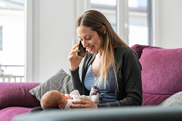 Giovane madre sul divano a parlare al telefono con un bambino al seguito